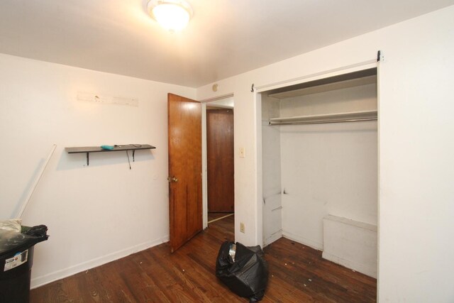 bedroom with dark hardwood / wood-style flooring and a closet