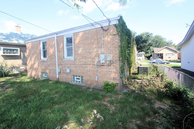 view of side of property with a yard, fence, and brick siding