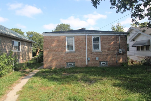 view of side of home with a yard, brick siding, and fence