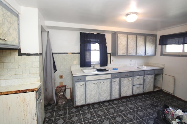 kitchen featuring plenty of natural light, light countertops, a sink, and gray cabinetry