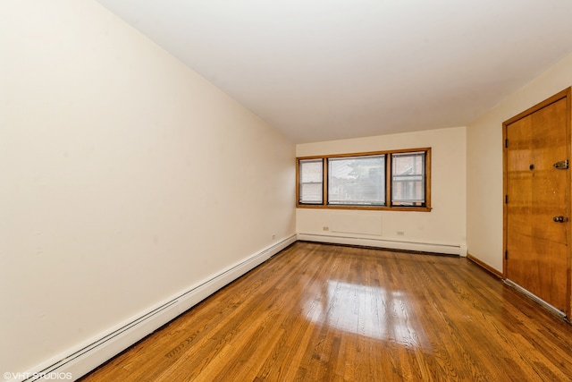 unfurnished room with vaulted ceiling, baseboard heating, and hardwood / wood-style floors