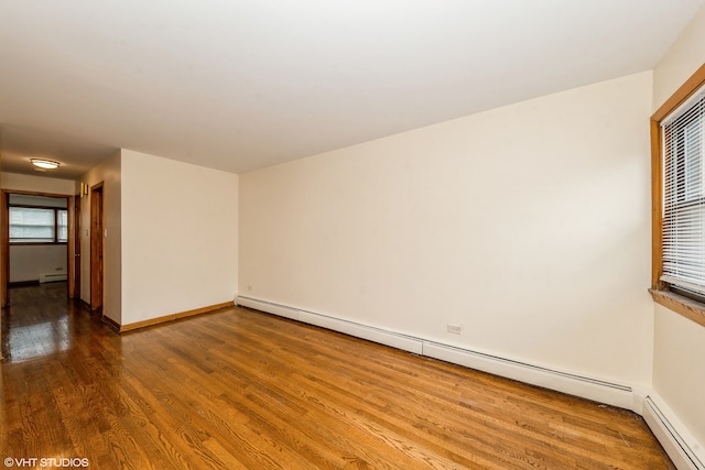 empty room featuring a baseboard radiator and hardwood / wood-style flooring