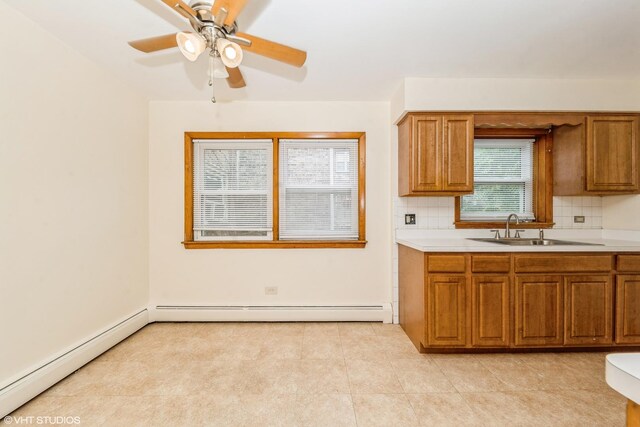 kitchen featuring baseboard heating, sink, ceiling fan, and tasteful backsplash