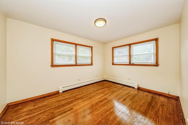 unfurnished room with baseboard heating and hardwood / wood-style floors