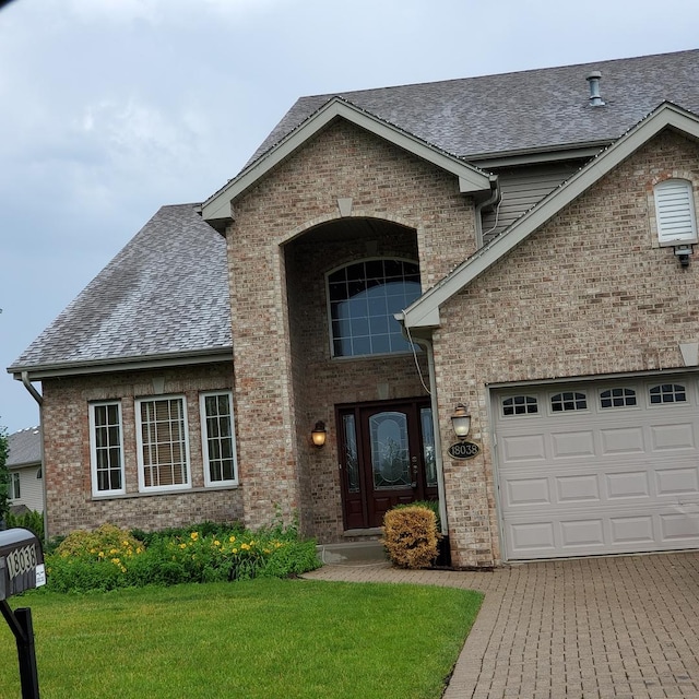 view of front of house with brick siding, roof with shingles, an attached garage, and a front yard