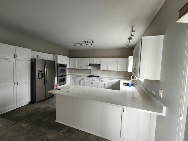 kitchen featuring kitchen peninsula, track lighting, stainless steel appliances, sink, and white cabinetry