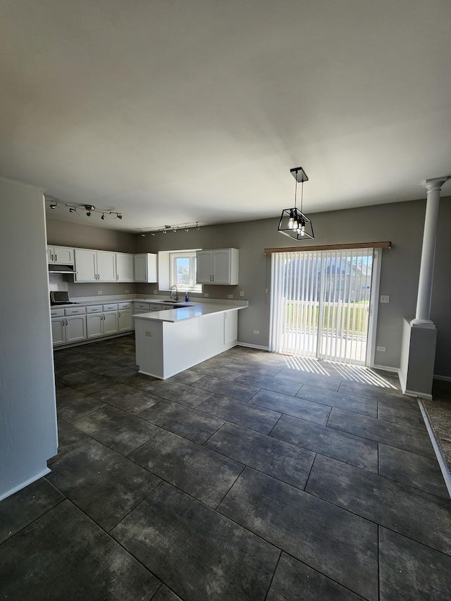 kitchen featuring a peninsula, a healthy amount of sunlight, white cabinetry, and a sink