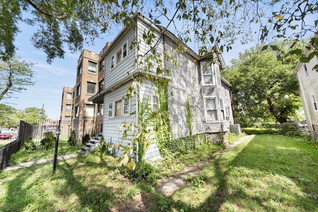 view of side of home with a lawn and central AC