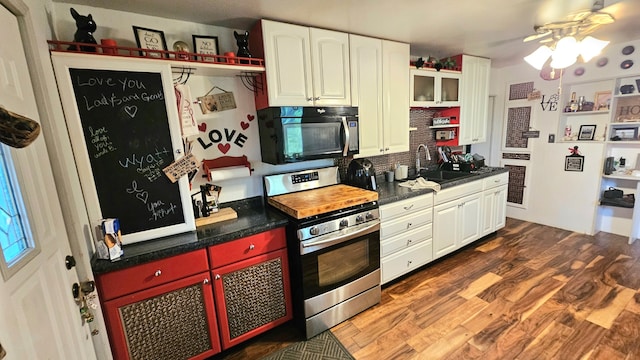 kitchen featuring decorative backsplash, white cabinets, stainless steel stove, dark wood-type flooring, and sink