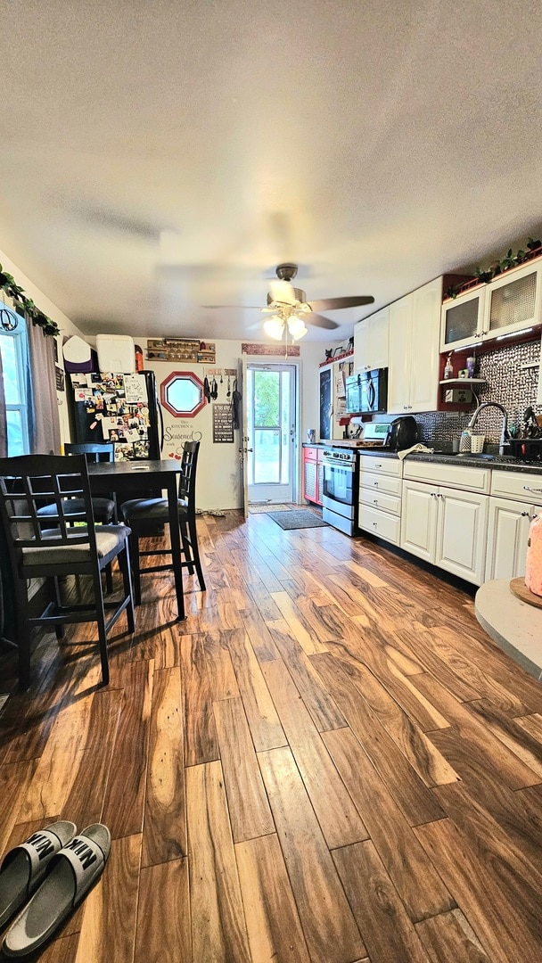 kitchen featuring white cabinetry, stainless steel range oven, hardwood / wood-style floors, and tasteful backsplash