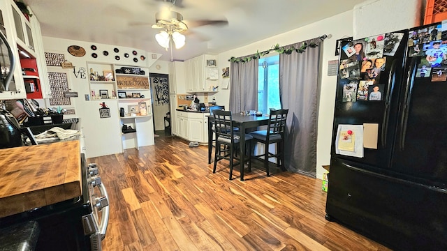 kitchen with wood counters, black fridge, hardwood / wood-style floors, ceiling fan, and white cabinets