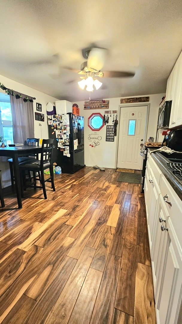 kitchen featuring black refrigerator with ice dispenser, white cabinetry, wood-type flooring, and ceiling fan