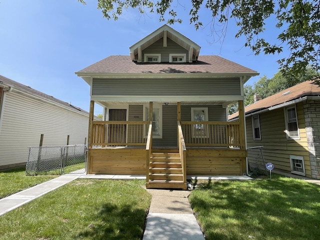 view of front of property featuring a front yard, fence, covered porch, and a shingled roof