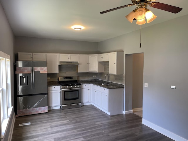 kitchen with baseboards, a sink, decorative backsplash, dark wood-type flooring, and appliances with stainless steel finishes