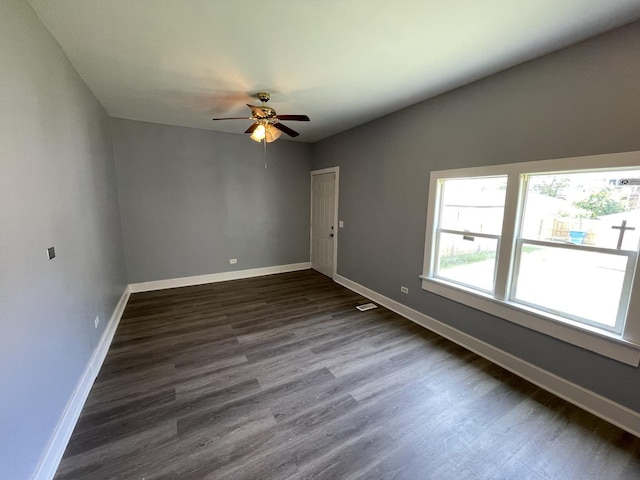 spare room with ceiling fan, dark wood-type flooring, and baseboards