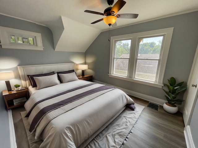 bedroom with wood finished floors, visible vents, baseboards, ceiling fan, and vaulted ceiling