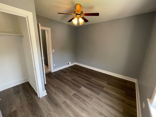 unfurnished bedroom with dark wood-type flooring, a closet, and ceiling fan