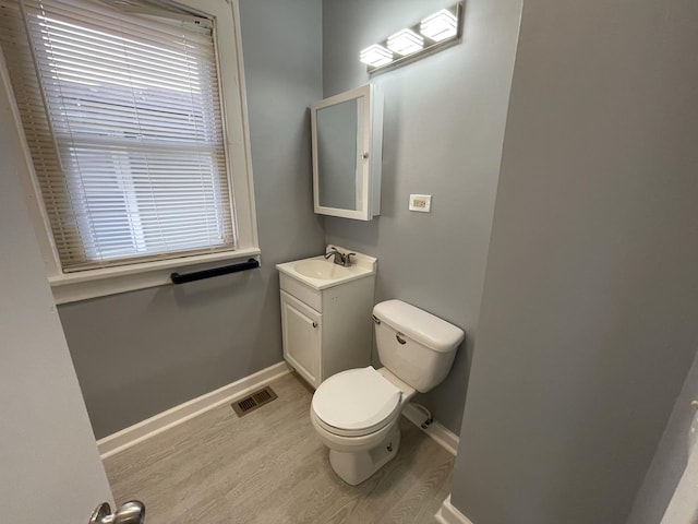 bathroom with toilet, vanity, baseboards, and wood finished floors
