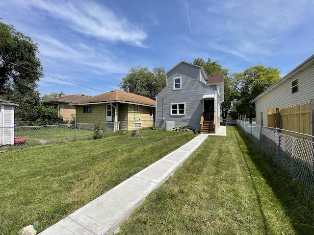 back of property with a lawn, fence private yard, and entry steps