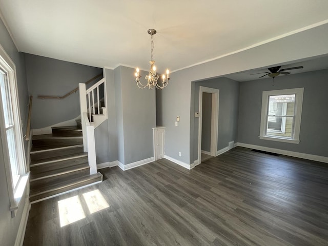 spare room with ceiling fan with notable chandelier, baseboards, stairs, and dark wood-type flooring