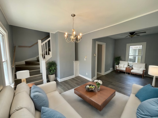 living area featuring stairway, baseboards, wood finished floors, and ceiling fan with notable chandelier