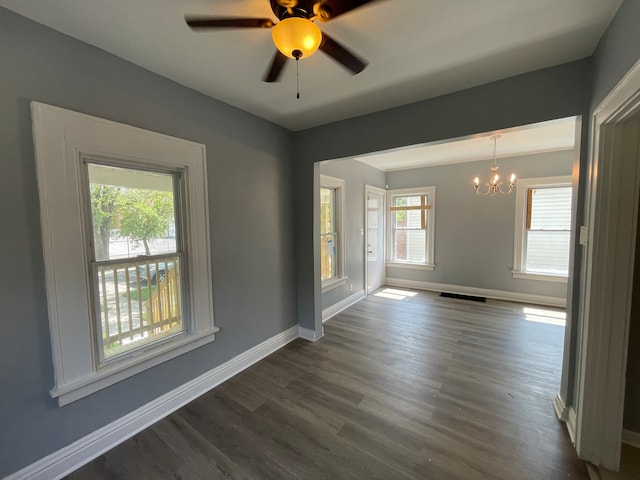 spare room featuring ceiling fan with notable chandelier and dark hardwood / wood-style flooring