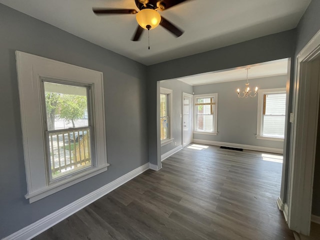 spare room featuring visible vents, baseboards, dark wood-style flooring, and ceiling fan with notable chandelier