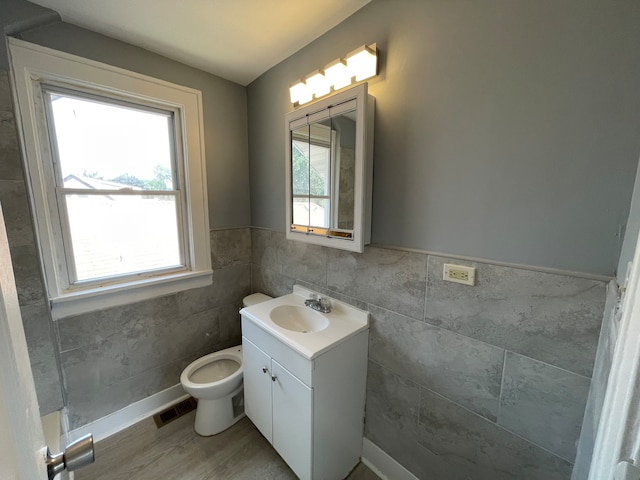 bathroom with vanity, toilet, tile walls, and wood-type flooring