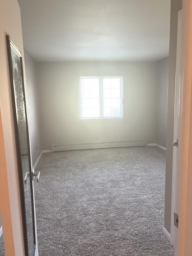 empty room featuring carpet, baseboards, and a baseboard heating unit