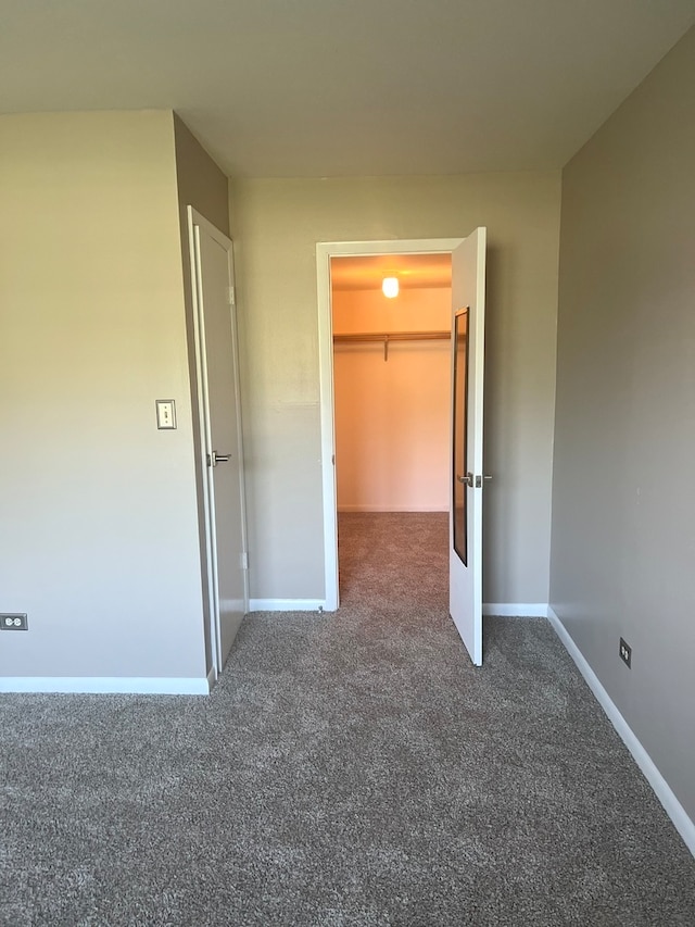 unfurnished bedroom with a closet, carpet flooring, and a walk in closet