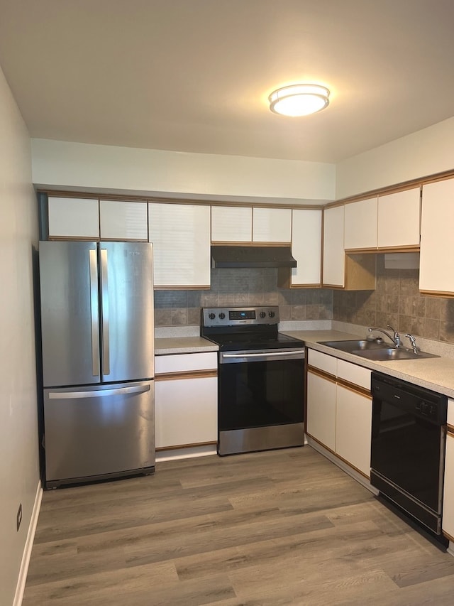 kitchen featuring wood-type flooring, stainless steel appliances, decorative backsplash, and sink