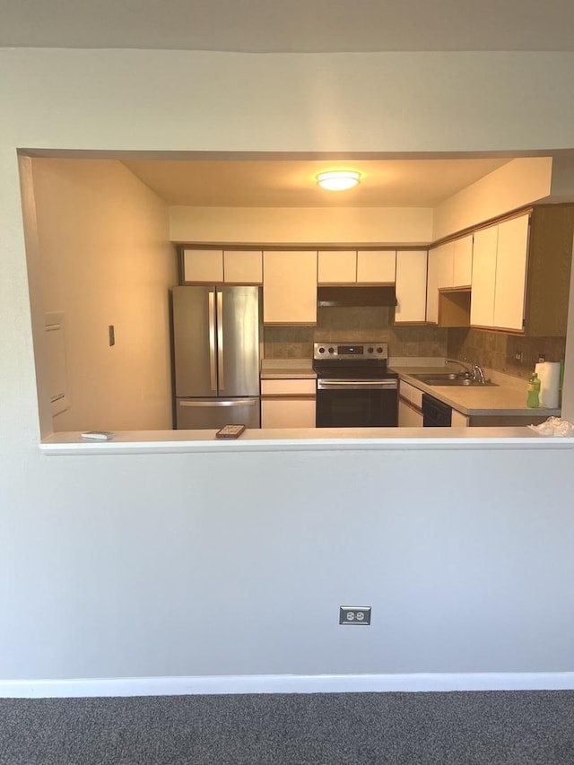 kitchen with stainless steel appliances, under cabinet range hood, white cabinetry, a sink, and backsplash