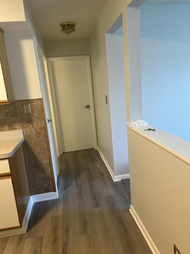 hallway featuring tile walls and dark wood-style floors