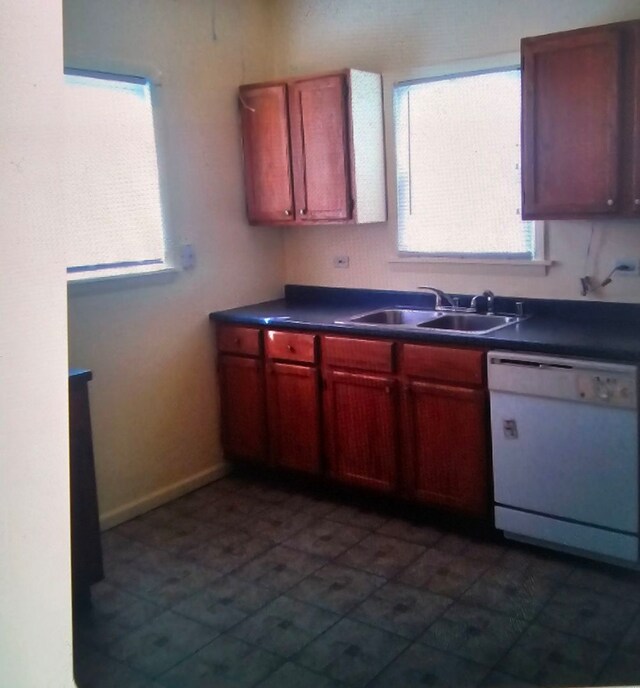 kitchen with white dishwasher, sink, and dark tile patterned floors