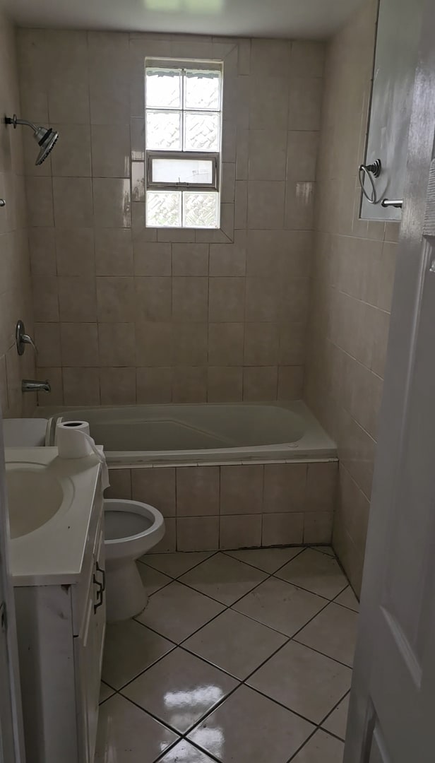 full bathroom featuring tile patterned floors, toilet, tiled shower / bath combo, and vanity