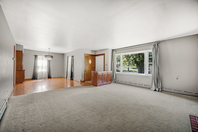 unfurnished living room featuring a baseboard heating unit and carpet