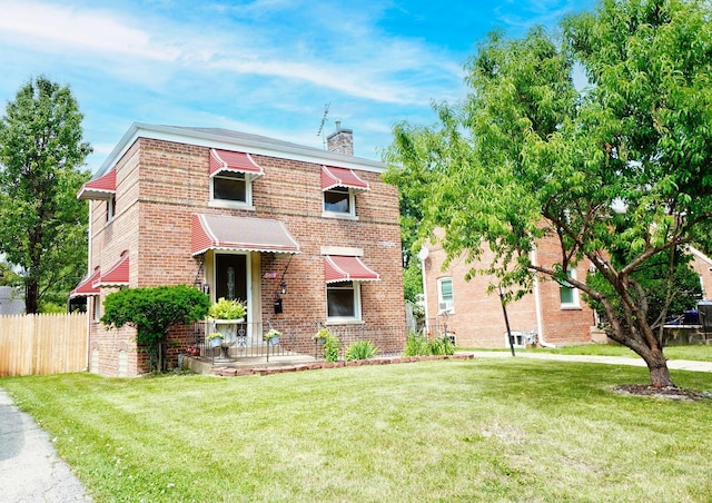 traditional-style home with brick siding, fence, a chimney, and a front lawn