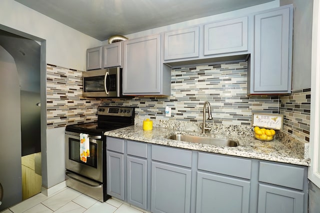 kitchen with backsplash, sink, light tile patterned floors, and stainless steel appliances