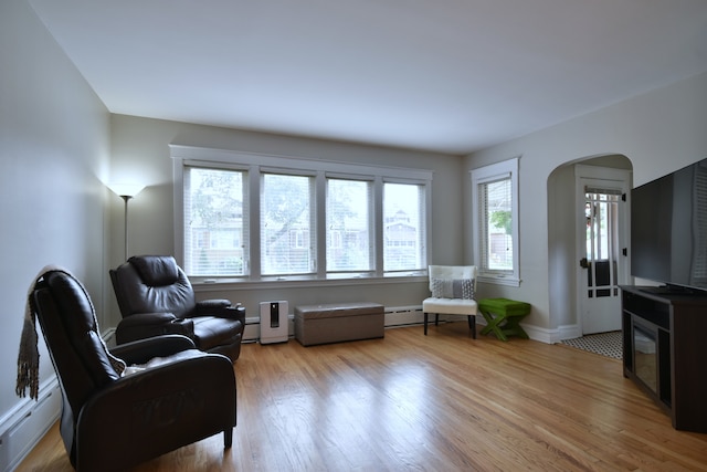 living area featuring baseboard heating and hardwood / wood-style floors