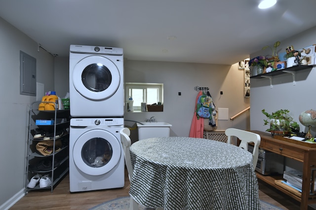 washroom featuring electric panel, hardwood / wood-style floors, and stacked washer and dryer