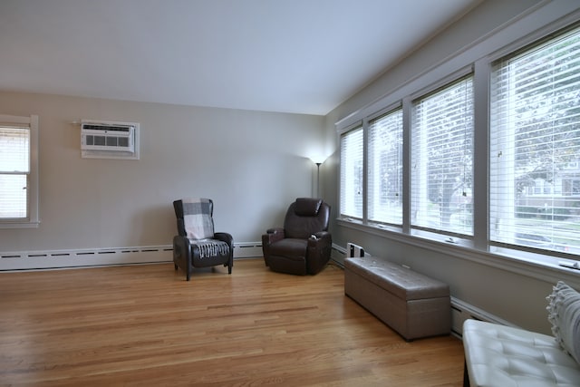 sitting room with hardwood / wood-style floors, a baseboard radiator, and a wall mounted air conditioner