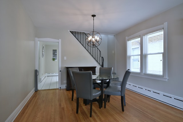 dining space featuring baseboard heating, a notable chandelier, and light hardwood / wood-style floors