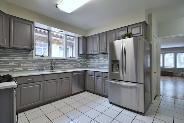 kitchen with gray cabinetry, appliances with stainless steel finishes, sink, light tile patterned flooring, and tasteful backsplash