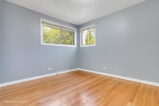 unfurnished room with baseboard heating and hardwood / wood-style floors