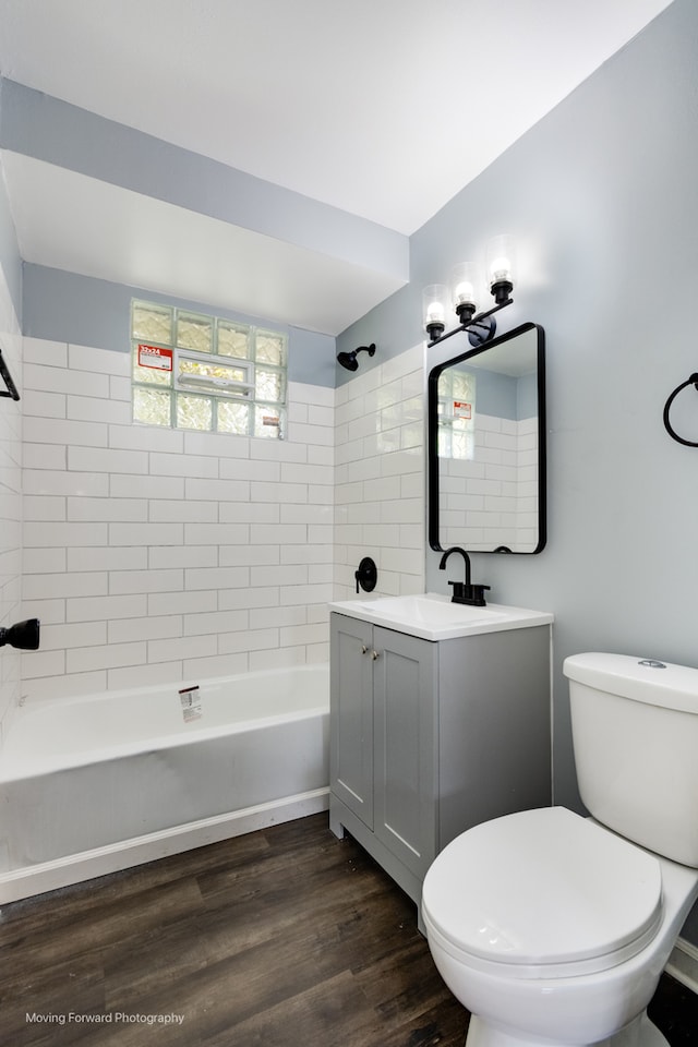 full bathroom with tiled shower / bath combo, vanity, toilet, and hardwood / wood-style flooring