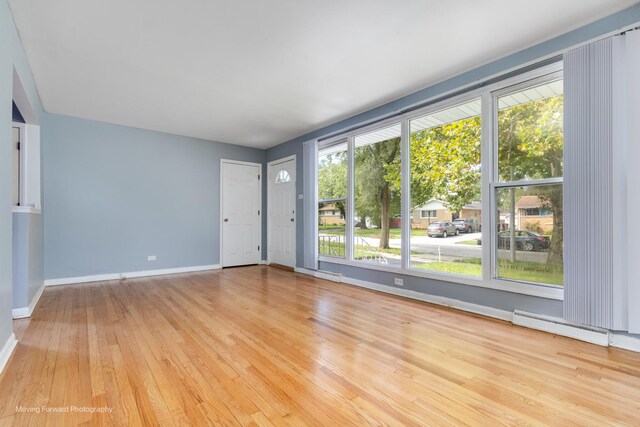 empty room featuring a baseboard radiator and light hardwood / wood-style floors