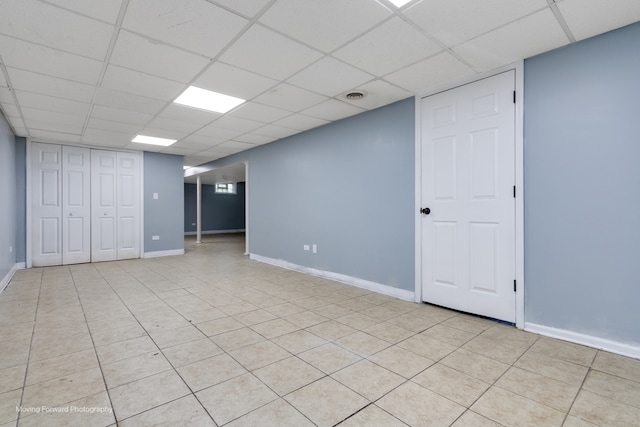 basement featuring a drop ceiling and light tile patterned flooring