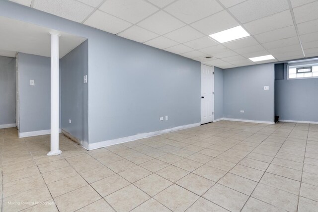 basement featuring light tile patterned floors and a drop ceiling