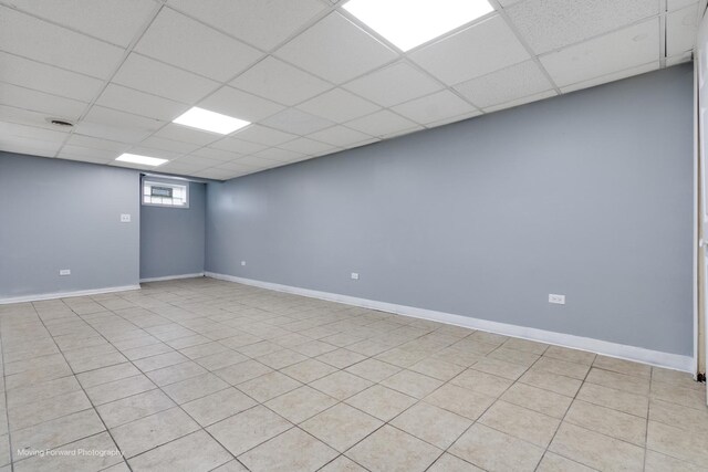 empty room with light tile patterned flooring and a drop ceiling