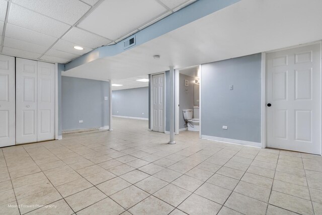 basement featuring light tile patterned floors and a drop ceiling